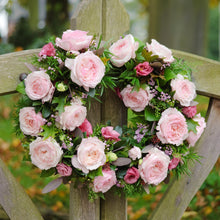 A wreath hanging  of Keira roses and greenery - Frilly wedding-dress petals frame her cupped blooms in every shade of soft pink, from raspberry ripple to clotted cream.