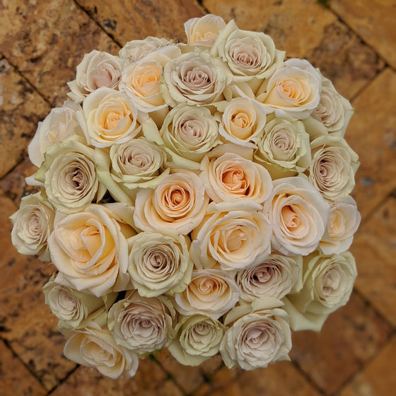 large bouquet of Cream color roses with hints of purple and orange. 