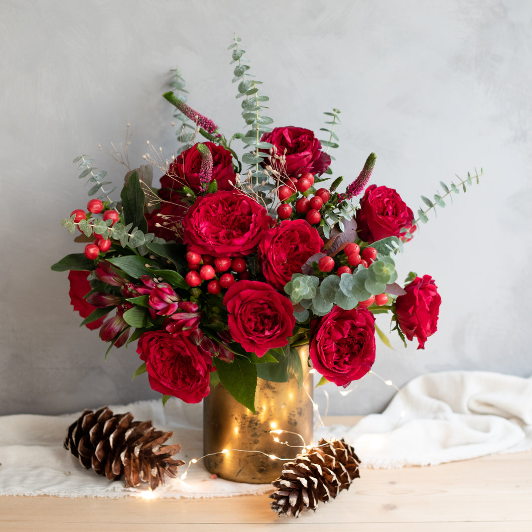 gold vase of close up of Tess roses with blackcurrant tones and richly ruffled rosettes with a glint of shimmering gold