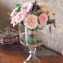 A vase on a table full of Keira roses - Frilly wedding-dress petals frame her cupped blooms in every shade of soft pink, from raspberry ripple to clotted cream. 
