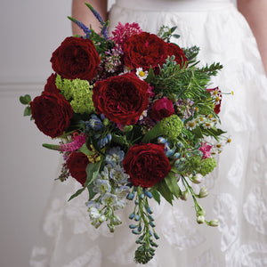 bride holding a bouquet of close up of Tess roses with blackcurrant tones and richly ruffled rosettes with a glint of shimmering gold