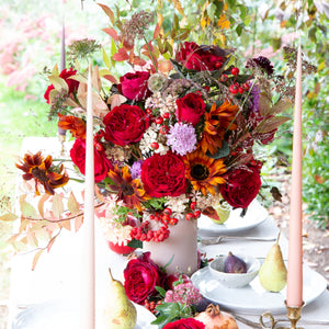 Wedding talbe setting of bouquet with  of Tess roses with blackcurrant tones and richly ruffled rosettes with a glint of shimmering gold