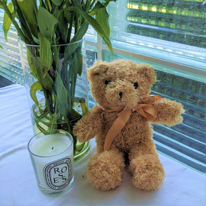 Teddy bear sitting next to a vase and candle